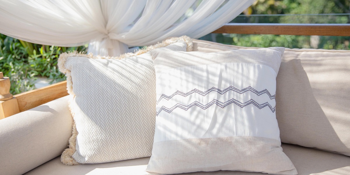 neutral colored outdoor cushions on an outdoor sofa bed with draped white cotton canopy gathered to corner